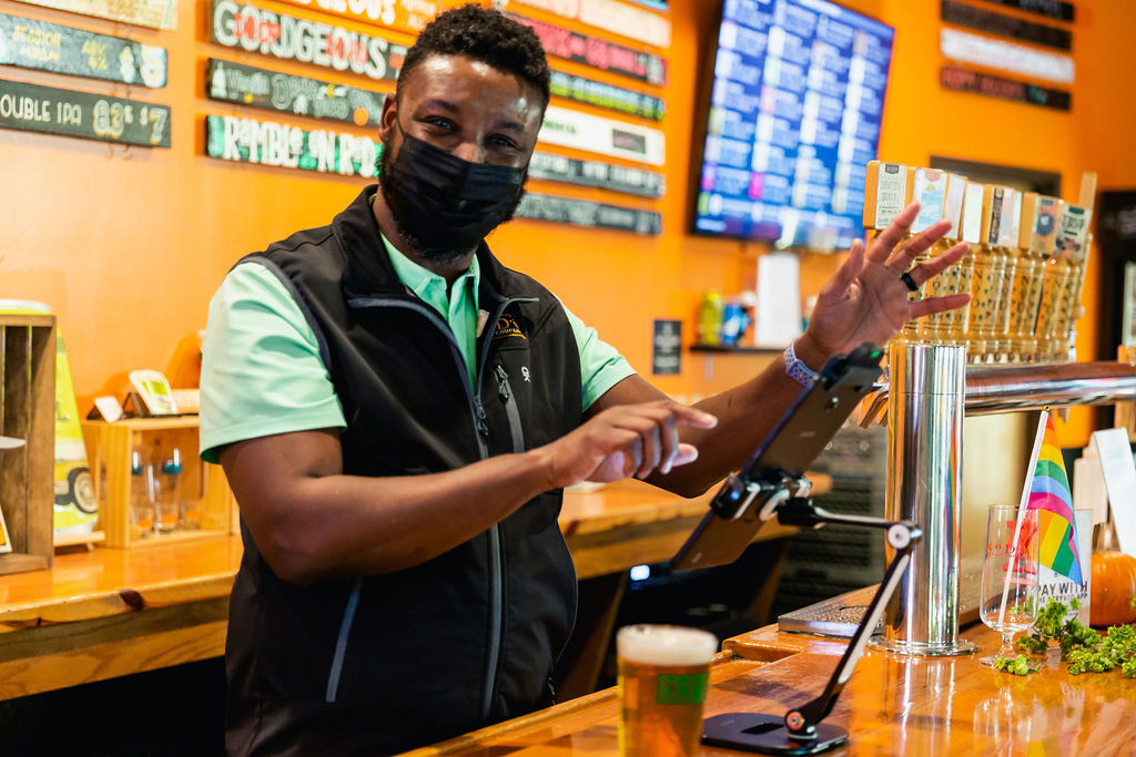 A friendly server waves from the taproom bar