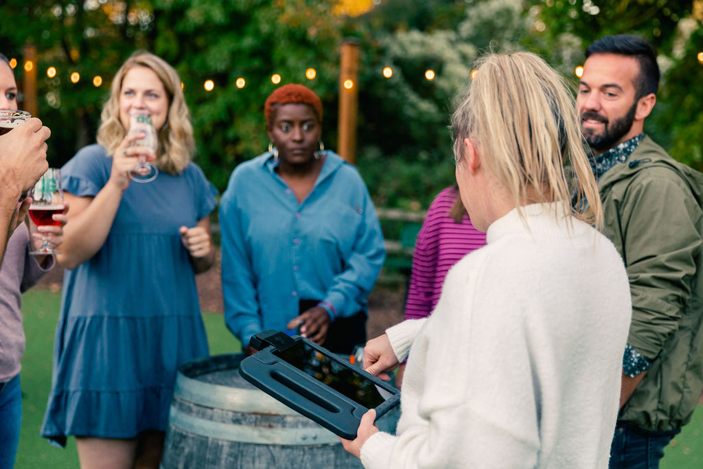 A server collects orders outside using a mobile POS tablet