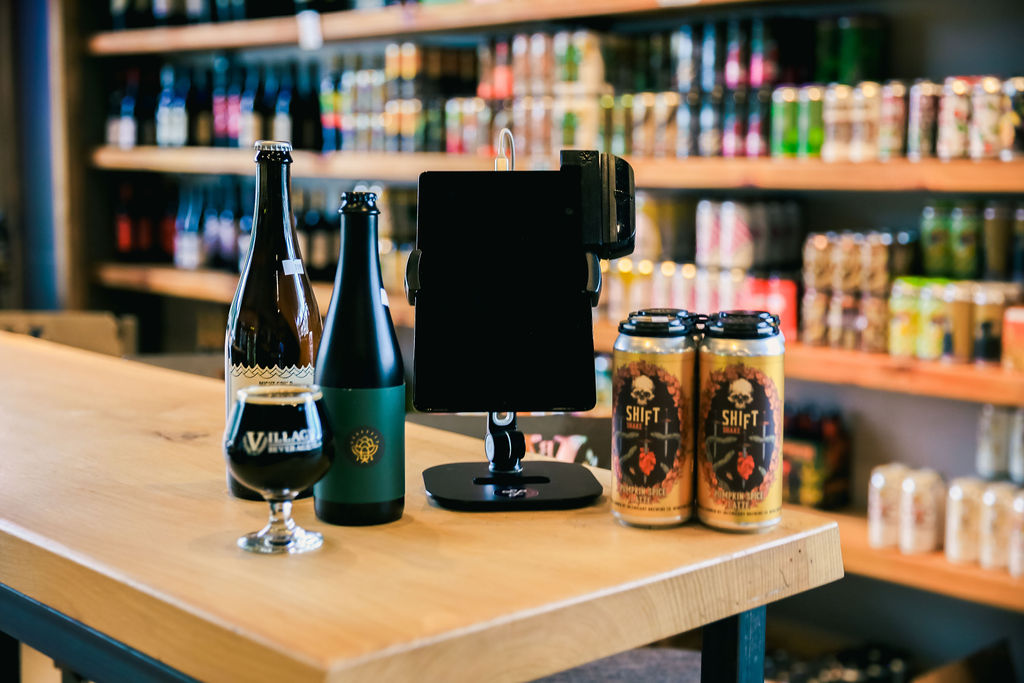 A mobile POS tablet + bottles, cans, and glasses of beer