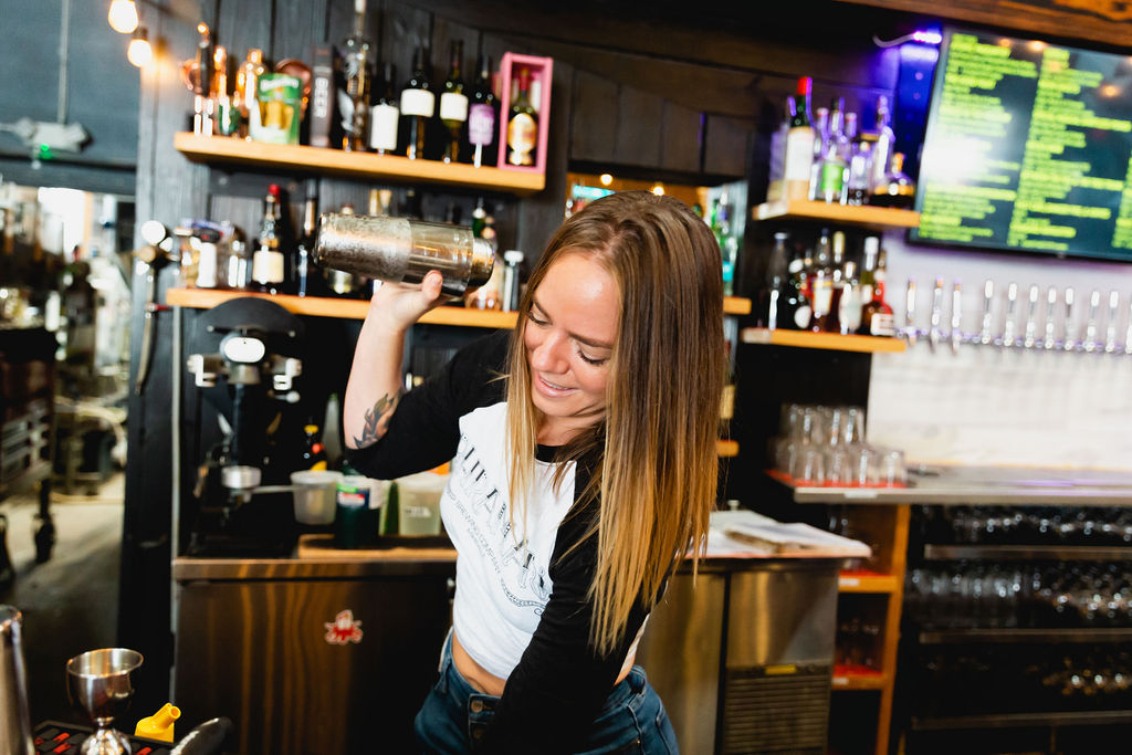 Bartender makes a cocktail before checking guest out on bar POS system