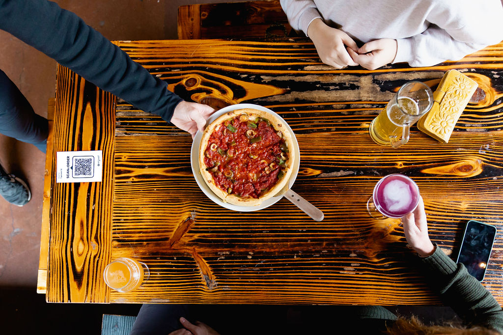 Server bringing out pizza to guests