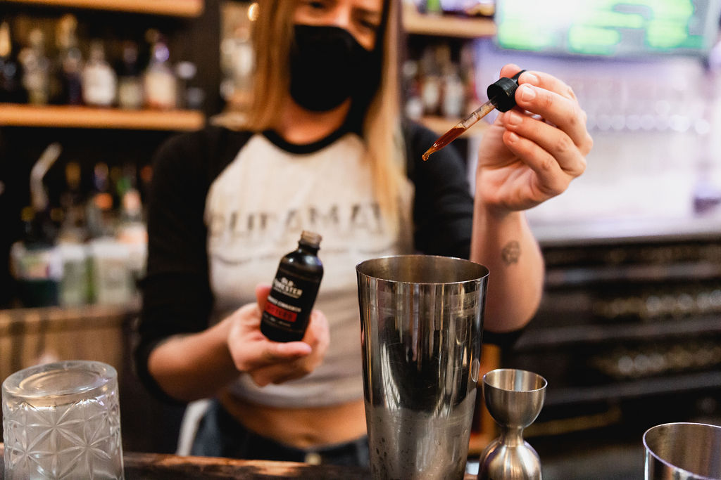 A bartender adds bitters to a cocktail