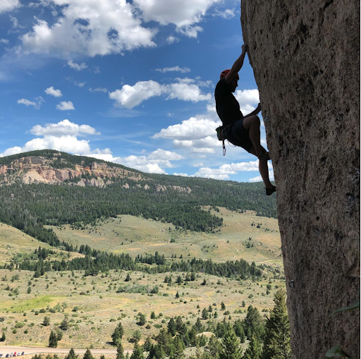 Arryved web developer, Ben Bauer, rock climbing with blue sky in the background.
