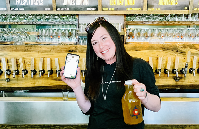 Beer tender with growler in one hand and phone showing the Arryved mobile app in the other