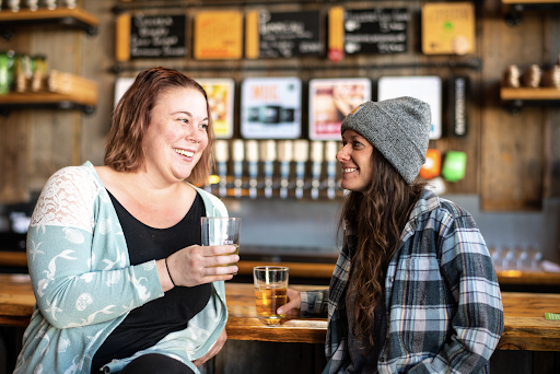 Two guests sitting at the bar looking at each other smiling