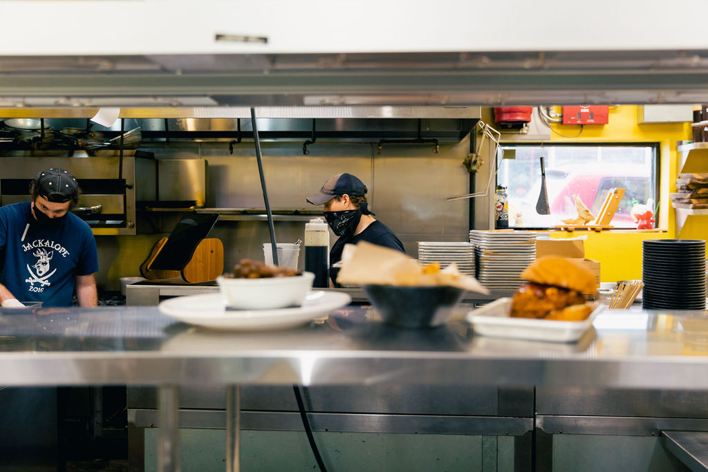 Kitchen staffing working in the kitchen preparing food with 3 plates under the heat lamp.