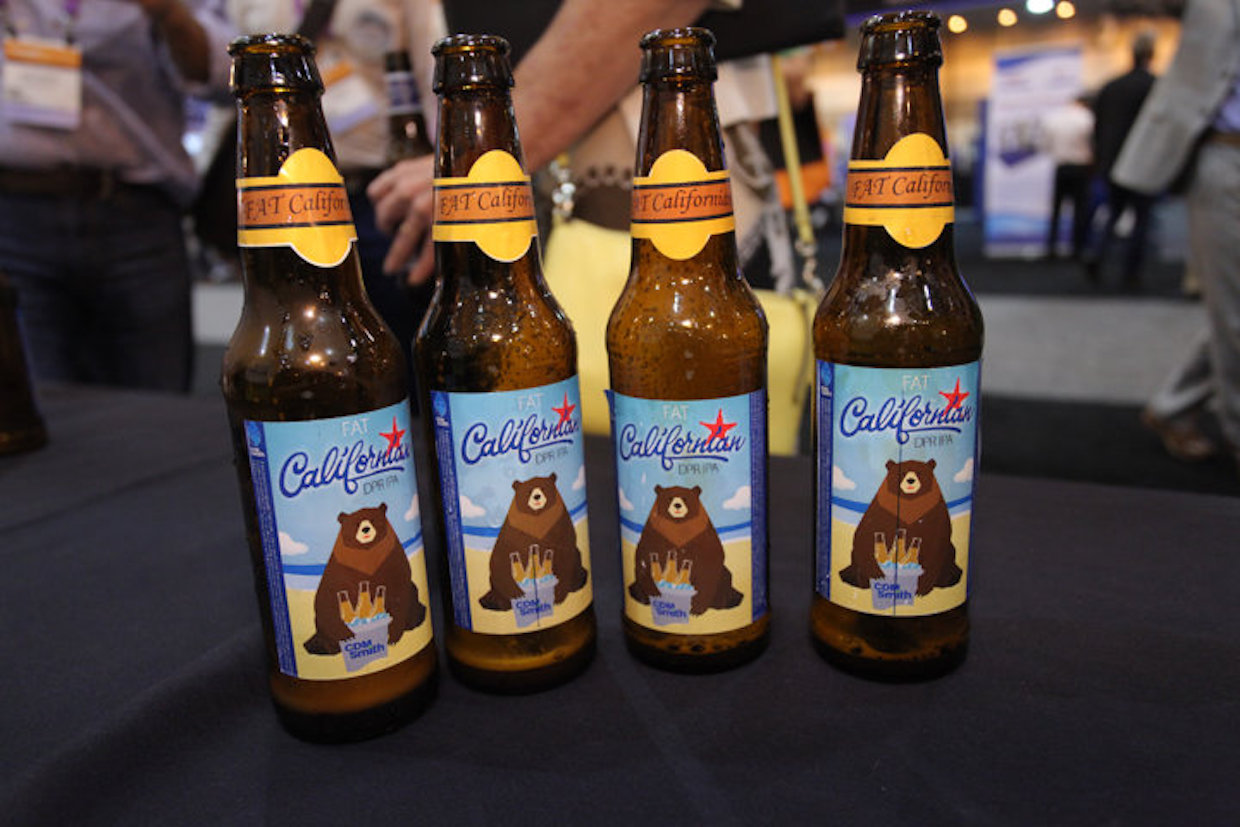 Four beer bottles with a bear sitting on the beach on the label.