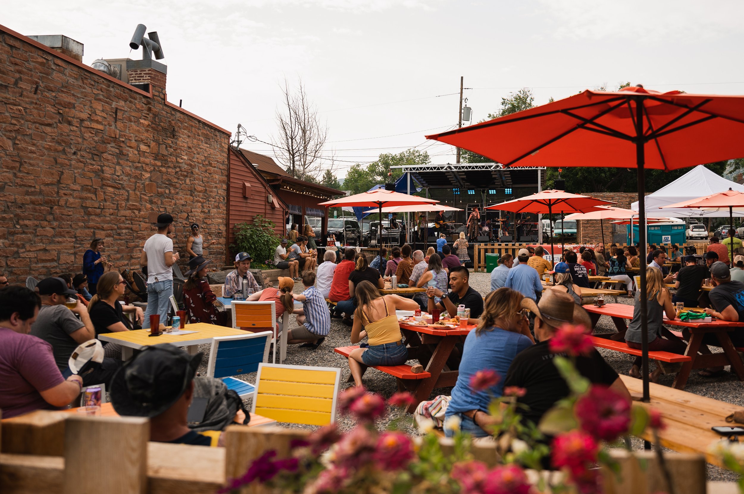 People sitting at tables on the patio at MainStage Brewing, a band playing in the background.