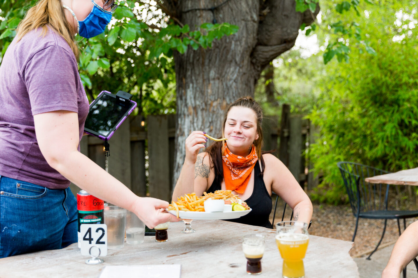 Guest eating a french fry off of a plate being set in front of her. 