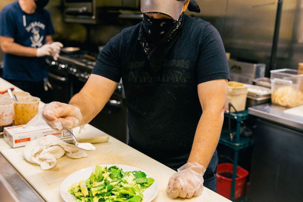 Cook adding cheese to a salad in the kitchen.